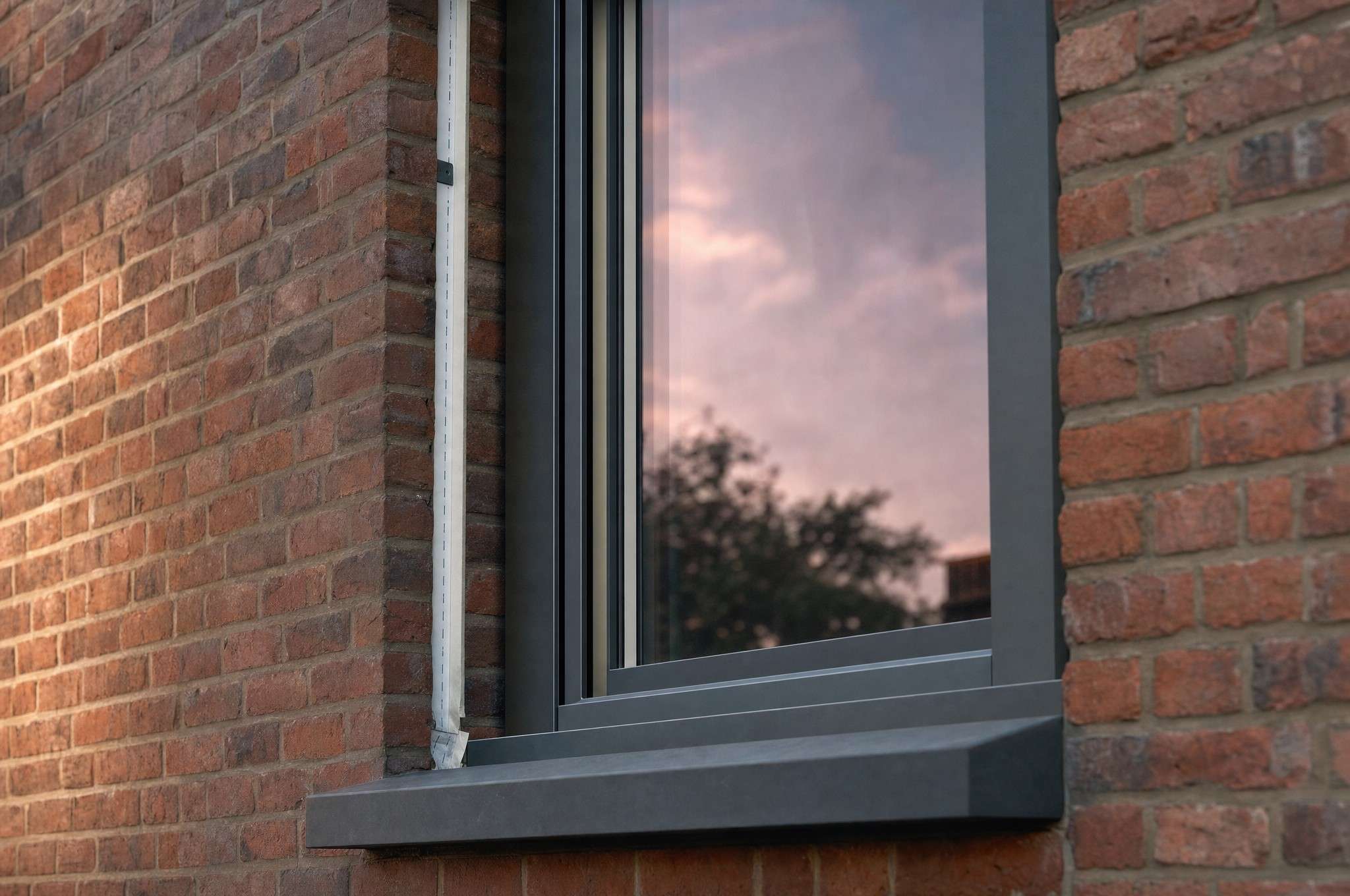 Châssis en aluminium anthracite neuf posé dans un mur en briques, ciel mauve dans le vitrage